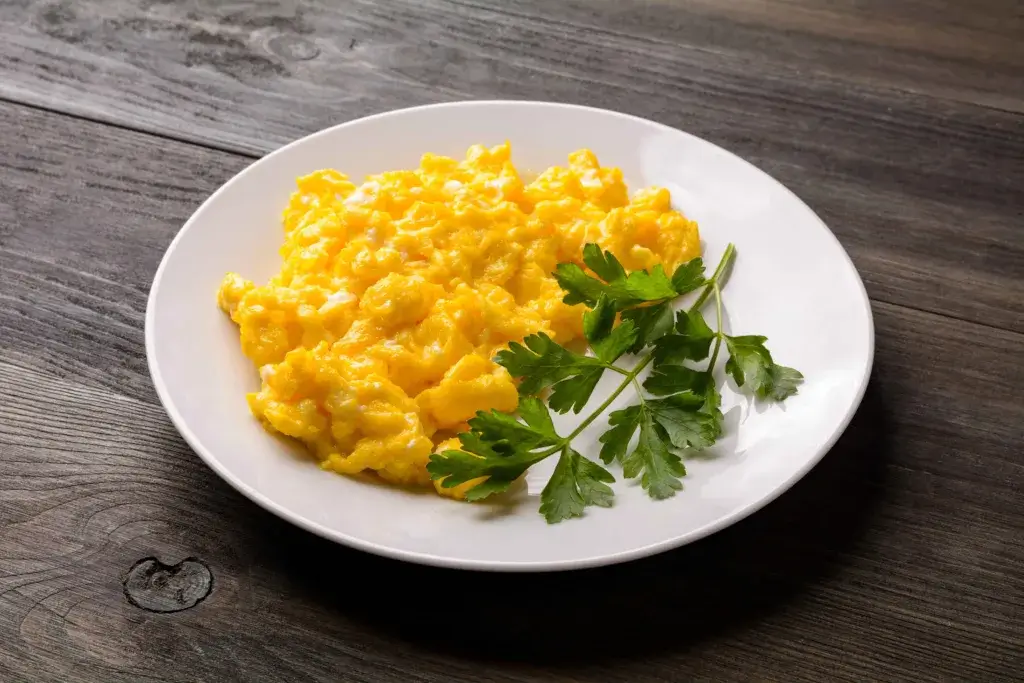 Cheesy scrambled eggs in a white bowl.