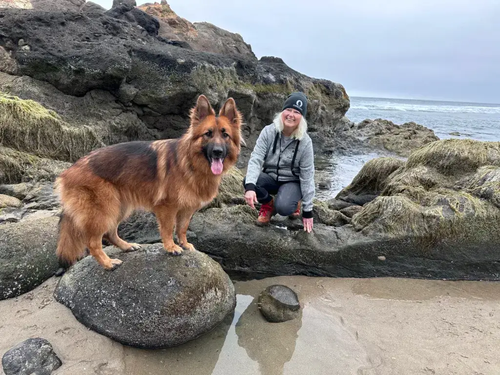 Woman and German Shepherd dog standing on rocks at the Oregon Coast.