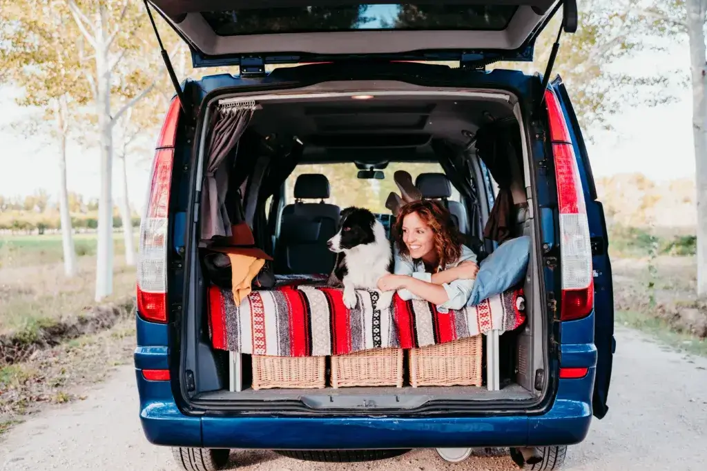 Young woman and her cute border collie dog relaxing in a van.