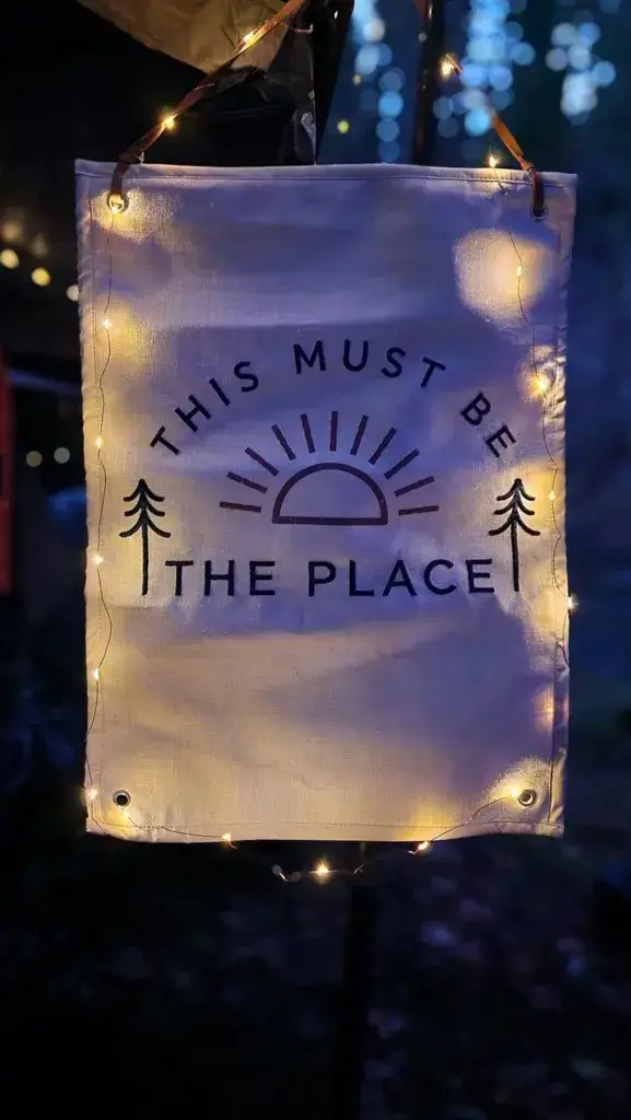 Sign that says This Must Be the Place with fairy lights strung around the sign.