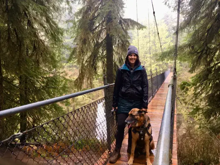 Woman and German Shepherd dog standing on a suspension bridge at Drift Creek Falls.