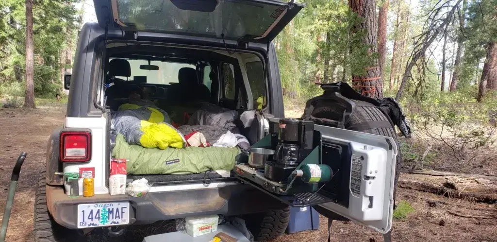 Jeep Wrangler with gate up showing car camping setup.