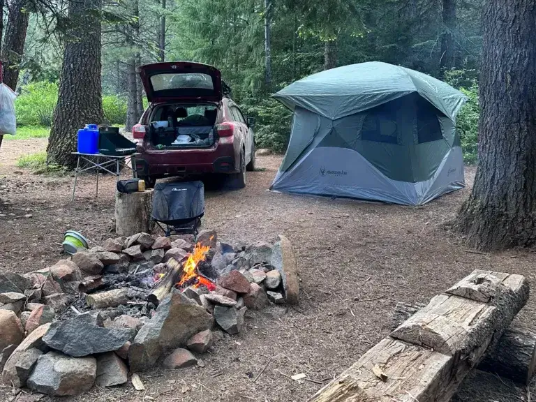 Campsite with a fire pit, parked Subaru Crosstrek and a Gazelle tent.