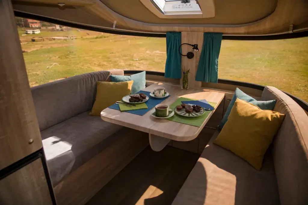 Pop up camper interior dinette area with a bench and table.
