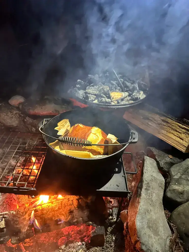 Cooking bread in a Dutch Over over a campfire.