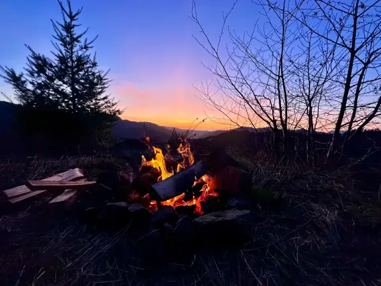 Campfire at sunset at a disbursed camping spot in Oregon.