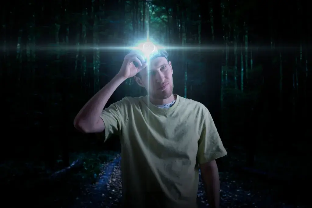 Man wearing a headlamp at camp in the woods.