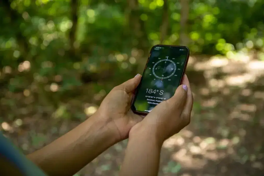 Young woman using compass on smart phone, close up of hands - best free hiking apps.