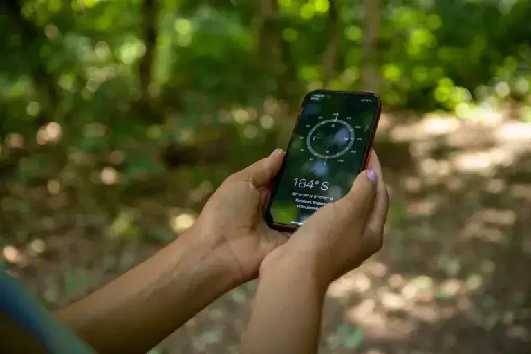 Young woman using compass on smart phone, close up of hands - best free hiking apps.