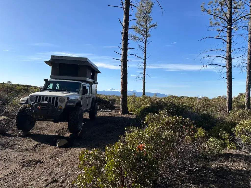 Jeep Gladiator with a popup tent in a camping spot with mountains in the background.