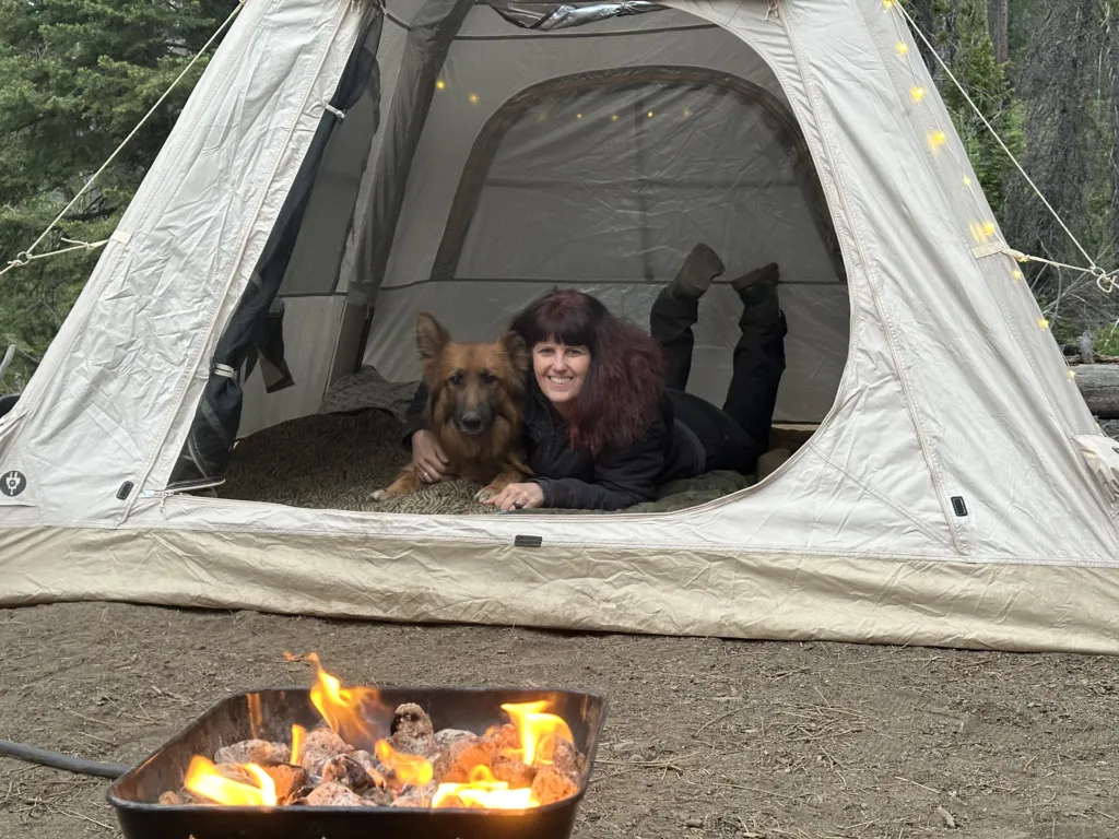 Woman and German Shepherd solo camping in a ground tent.