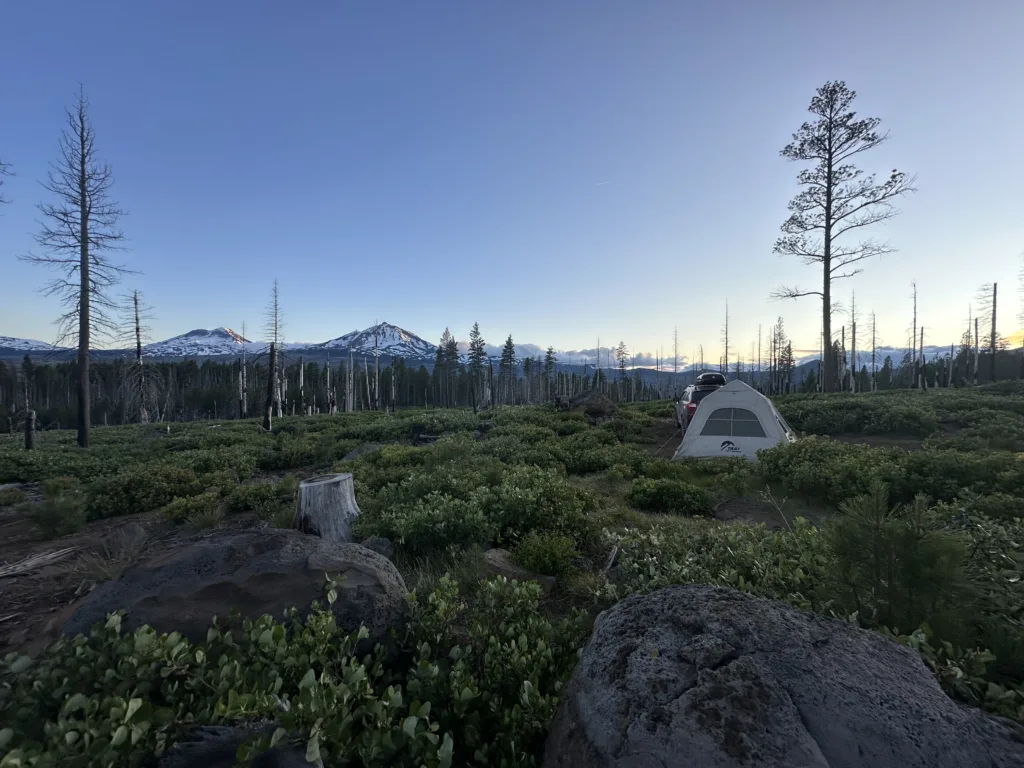 Solo camping tent with mountains in the background.