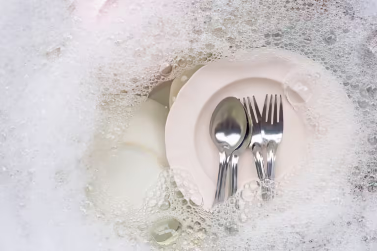 Washing dishes, Close up of utensils soaking in kitchen sink.