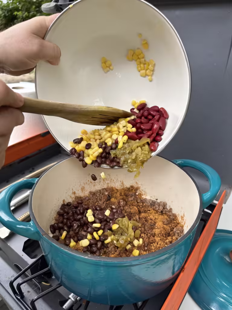 Pouring ingredients into a pot for camp Taco Soup.