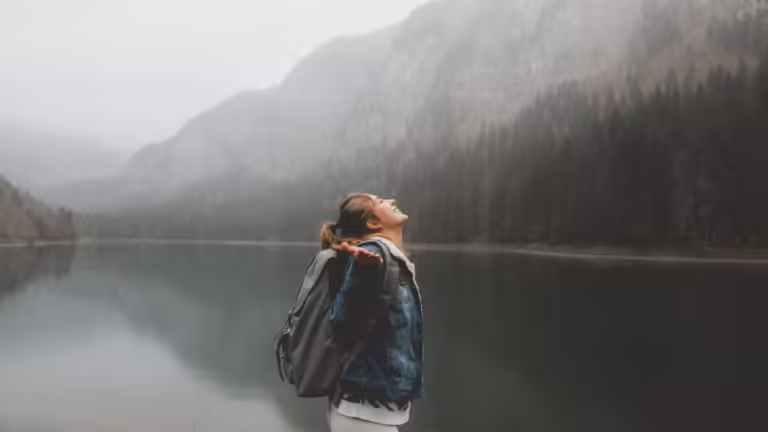 Attractive female hiker enjoys the view of lake Montriond in French Alps on a rainy day.