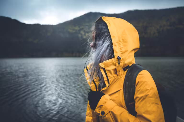 Close up view of a hiker enjoying rainy weather. Hiker wearing yellow waterproof raincoat sportswear clothes,