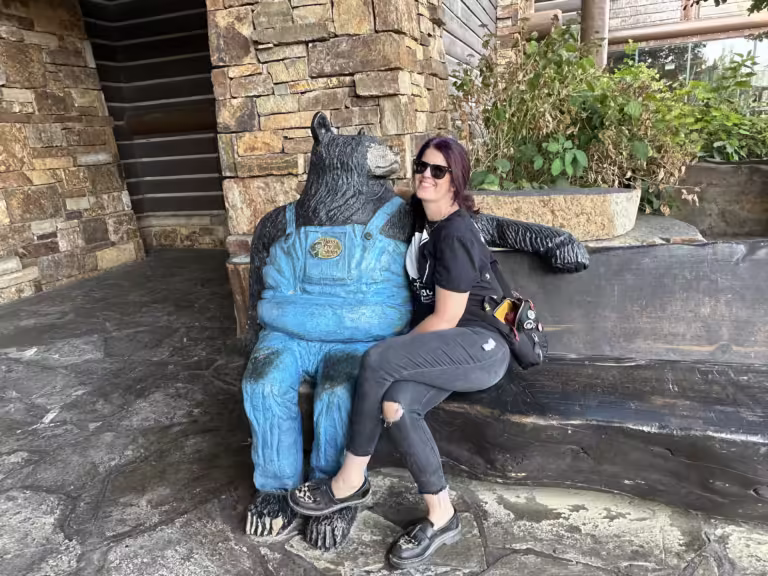 Woman sitting on a bench next to a bear statue.