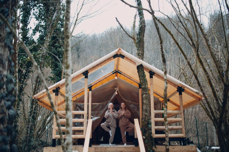 Two women doing yoga in their pajamas in a glamping cabin.