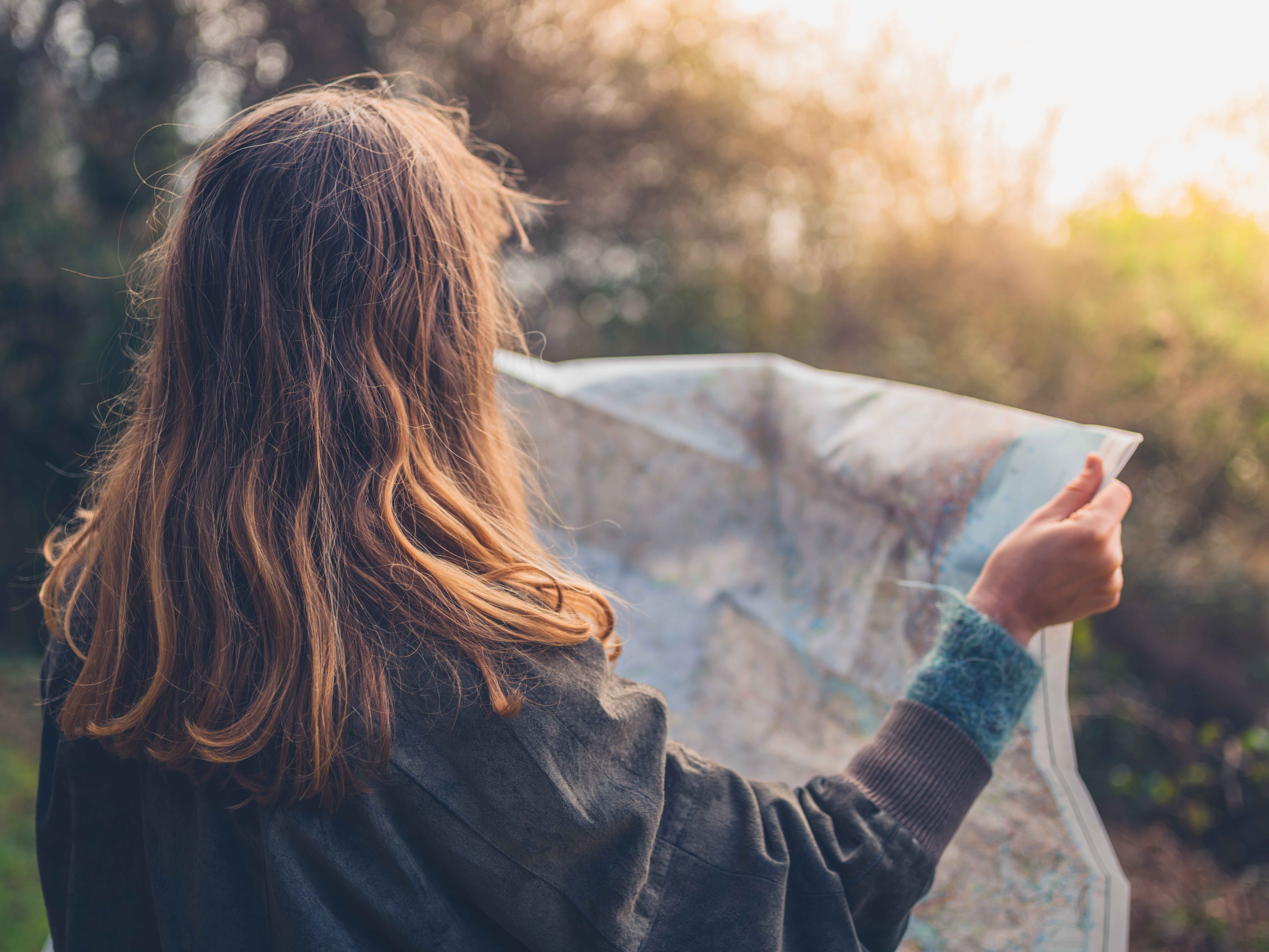 Woman on a hike looking at a paper map.