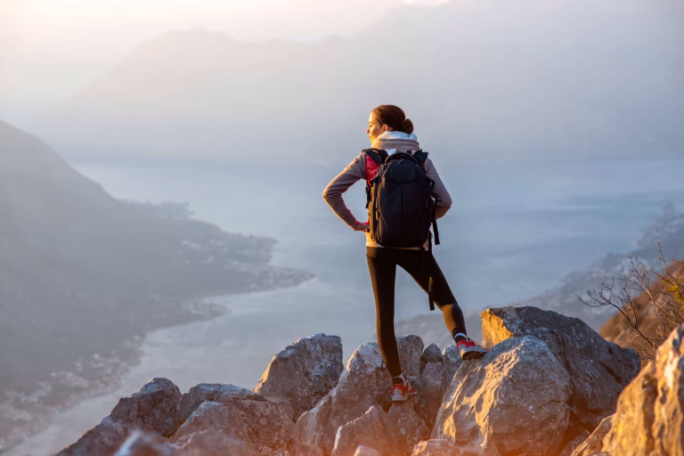 Woman on a solo hike looking at the valley below the mountain peak.