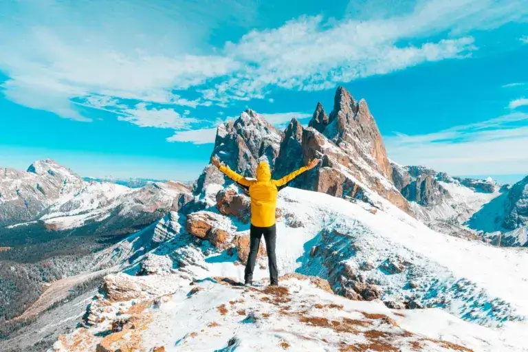 Woman hiking on a mountain wearing a yellow jacket.