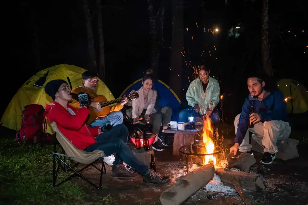 A group of friends is sitting around a campfire laughing and having fun.