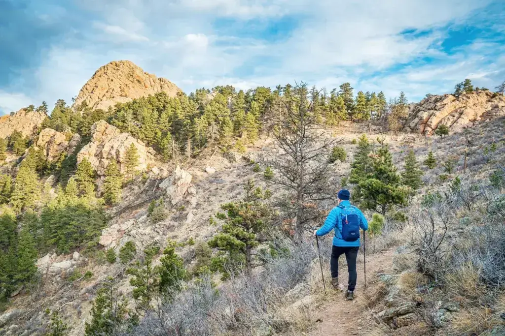 Man winter hiking wearing a blue jacket and backpack.