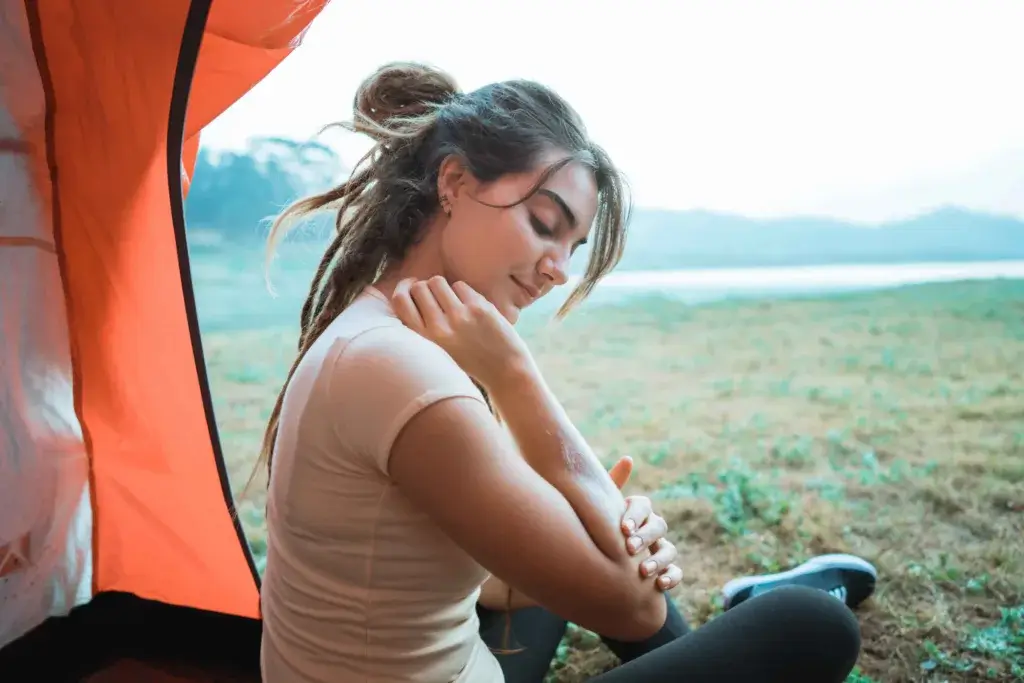 Young woman in a tent in a grassy field solo camping.