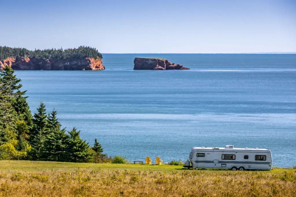 Unhitched travel trailer boondocking on a cliff with an ocean view.