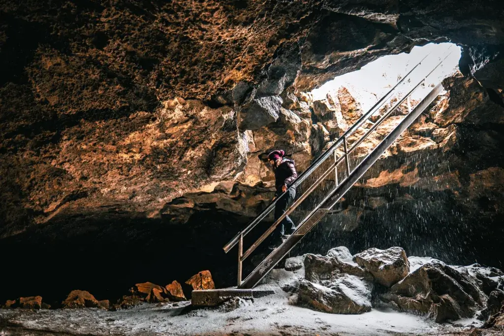 Woman going down the stairs into an underground cave.