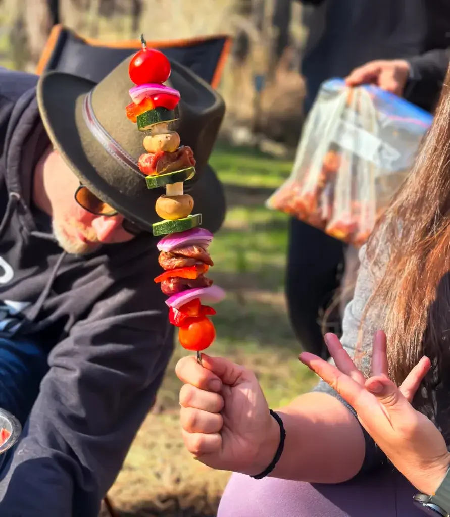 Woman holding up a colorful vegetable kebab.