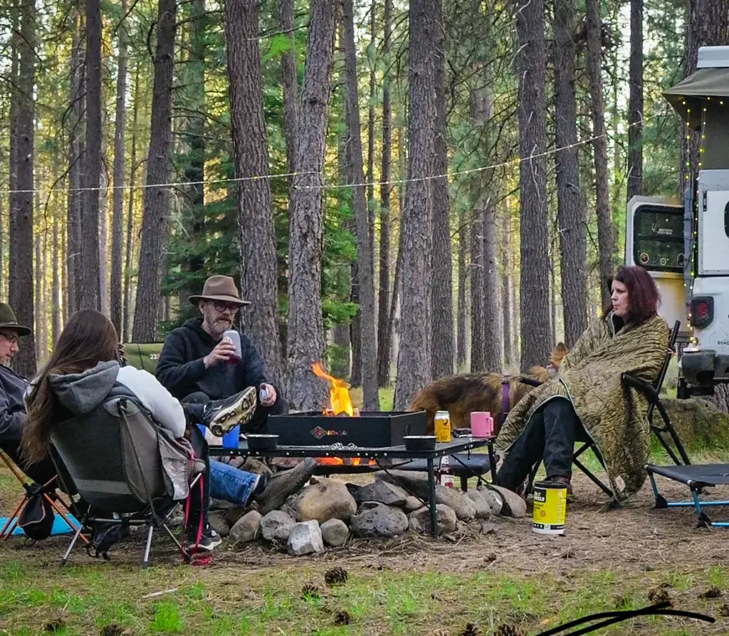 A group of friends sitting around the AroundFire fire pit, enjoying a fire and beverages.