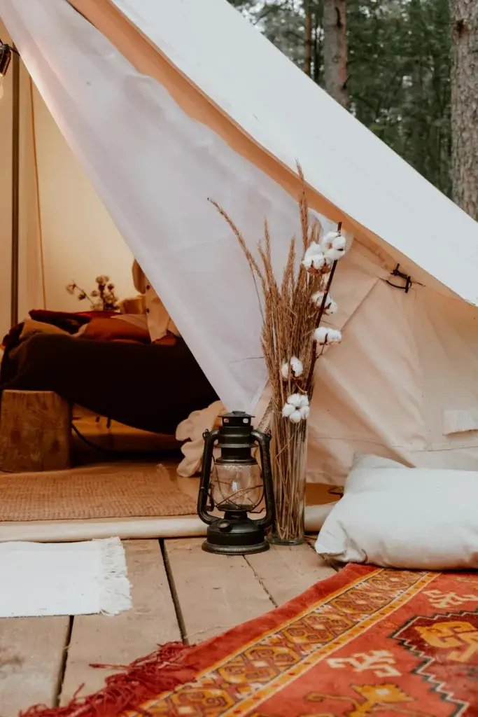 Inviting glamping setup with a cozy interior, featuring rustic decor and a classic lantern outside the tent.