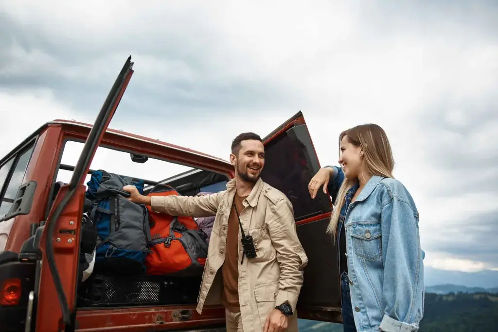 Young couple loading backpacks into the trunk on a roadtrip.