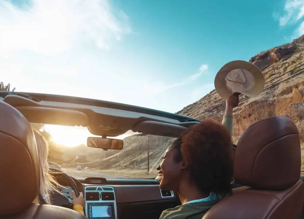 Two women in a convertible car on a roadtrip.