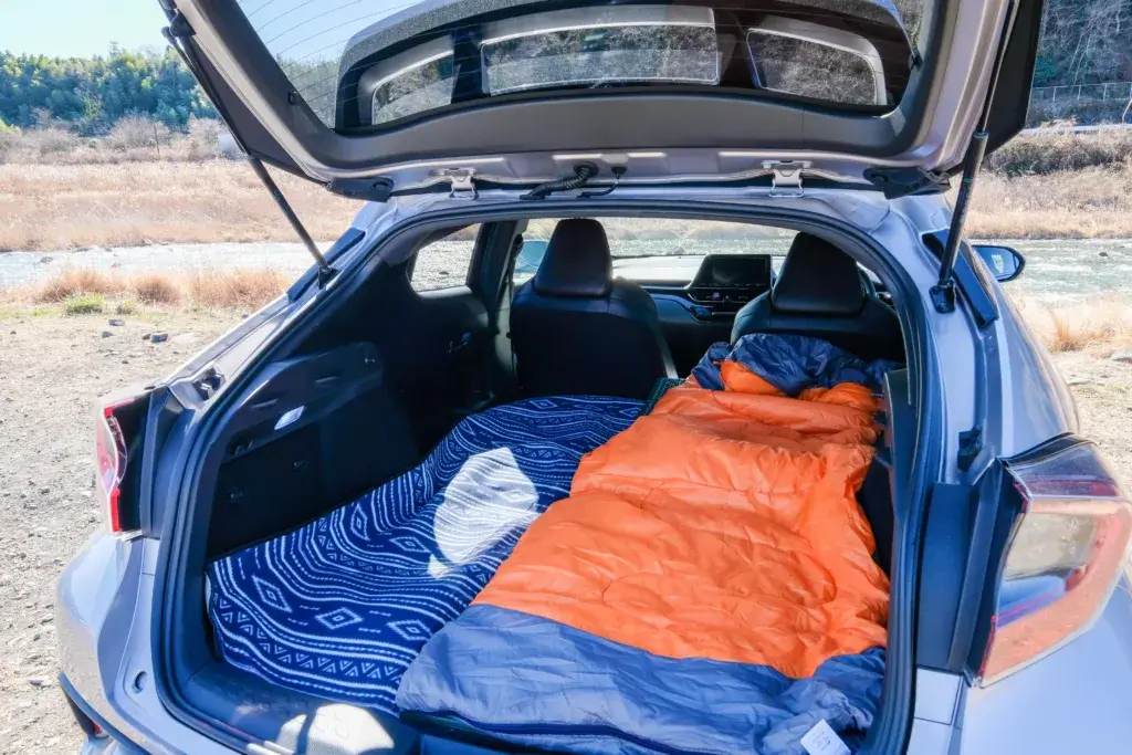 Hatchback with hatch open and a sleeping bag in the back setup for car camping.