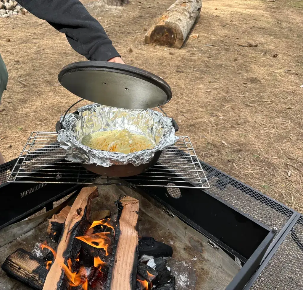 Ranch Mac N Cheese ingredients in a Dutch Oven over a campfire.