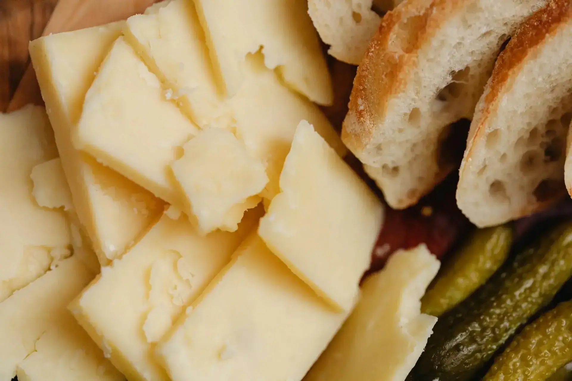 Delicious assortment featuring sliced cheese, rustic bread, and pickles, perfect for gourmet presentation.