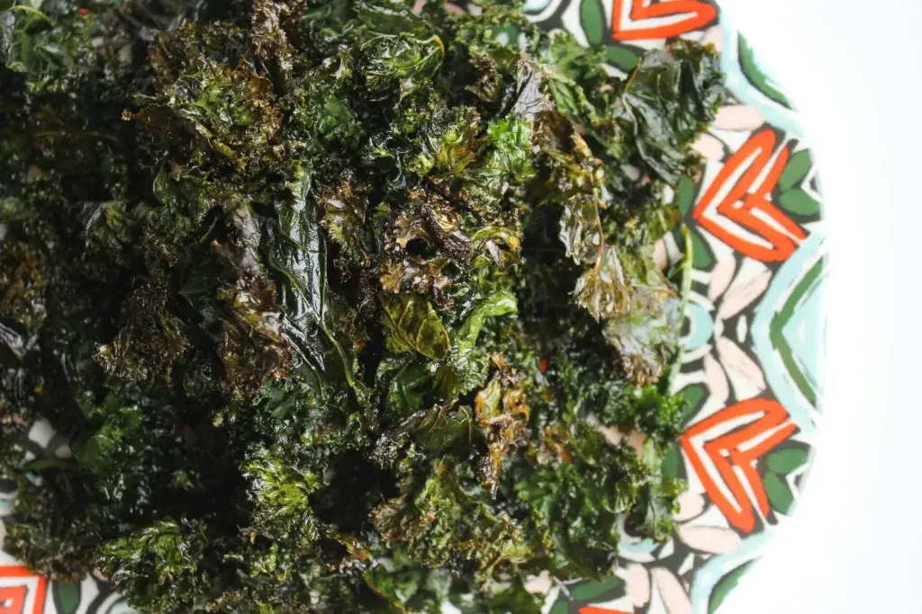 Delicious homemade baked kale chips served on a colorful patterned plate.