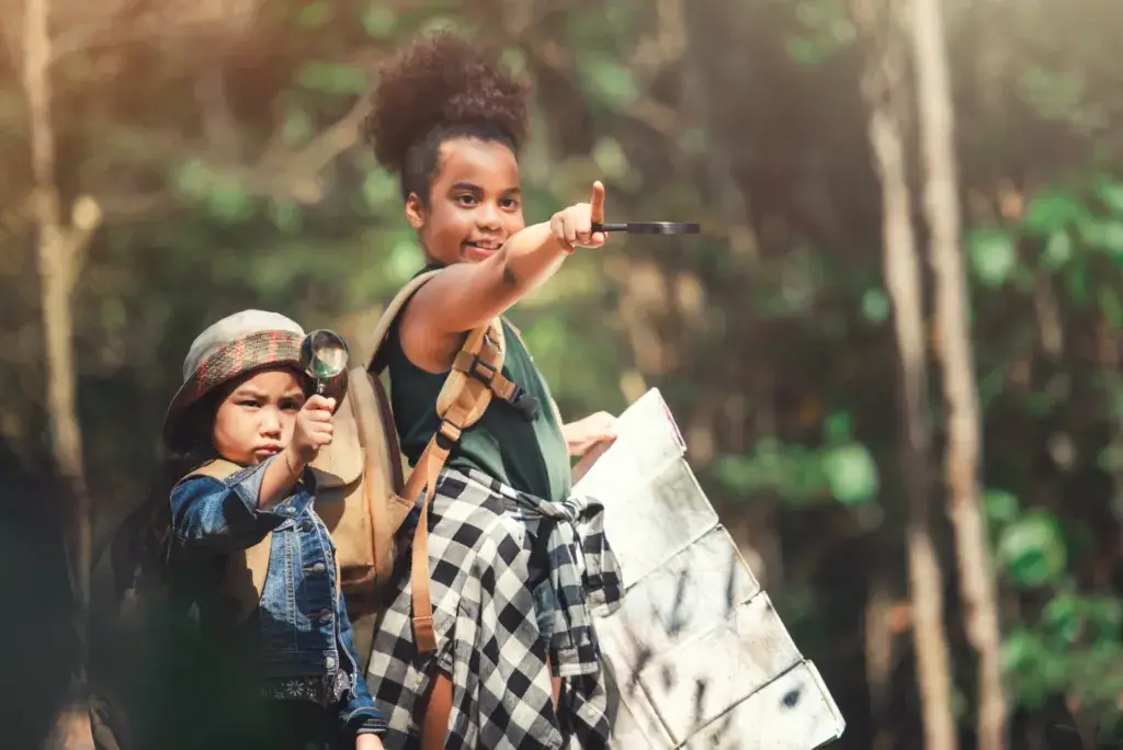 Two young children holding a map and magnifying glass on a scavenger hunt.
