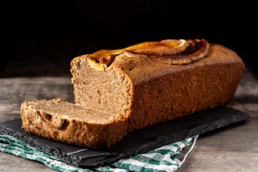 Loaf of banana bread with one slice cut off.