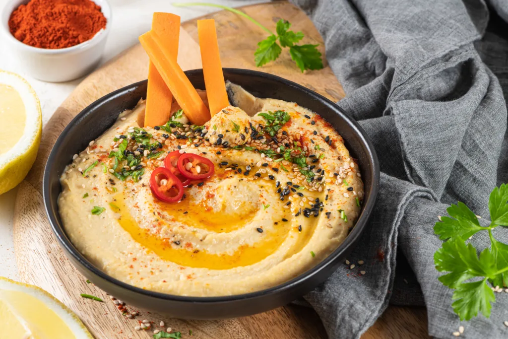 Bowl of hummus with carrot slices.