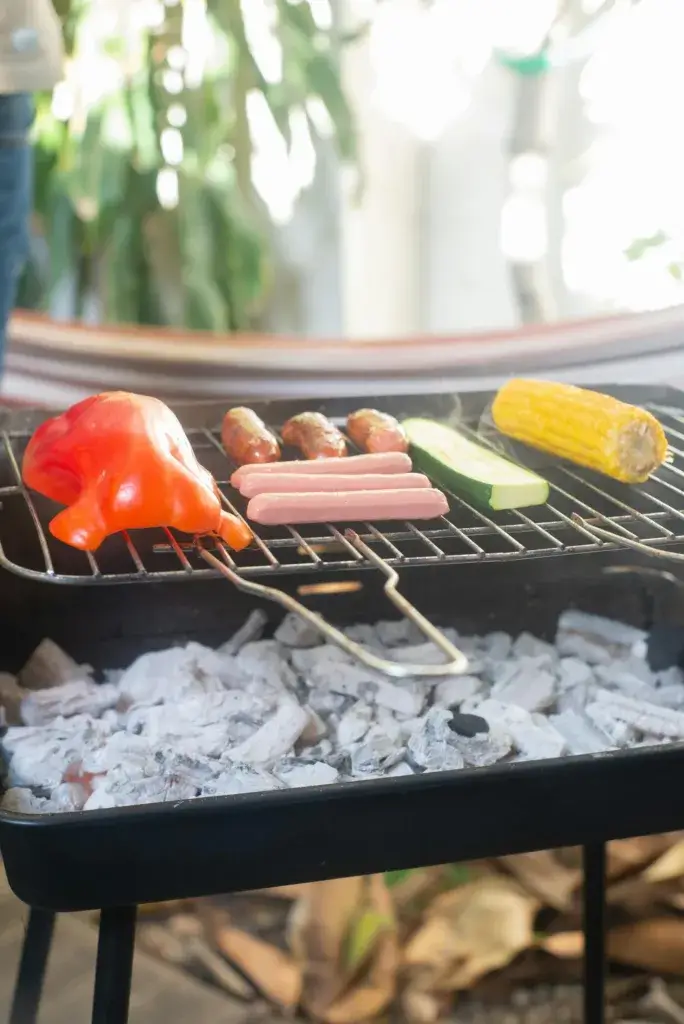Close-up of a variety of meats and vegetables grilling over charcoal.