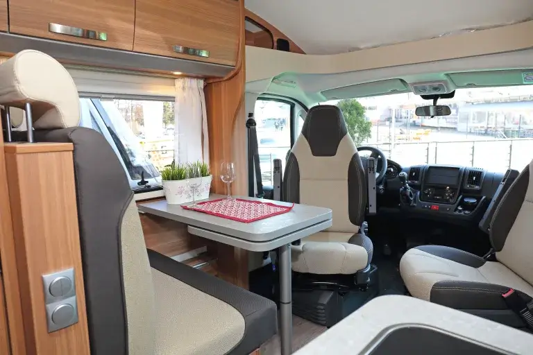 Camper van with a small dinette and swivel chairs.