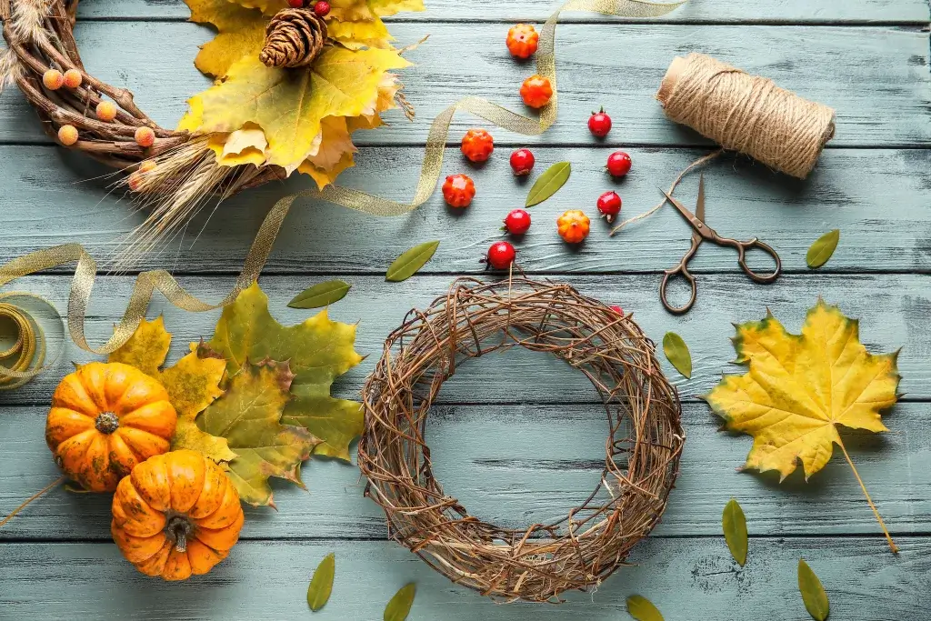 Picnic table with tools to make a fall autumn wreath including twine, scissors and mini pumpkins.