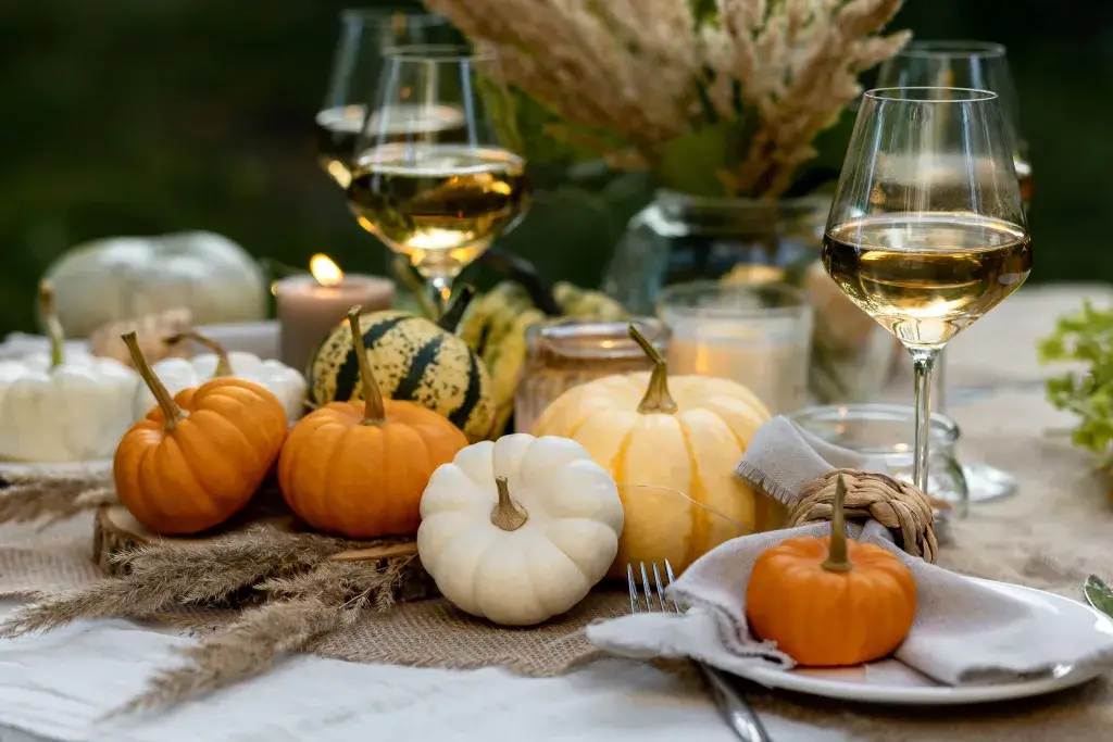 Mini pumpkins and gourds on a picnic table with two glasses of wine.