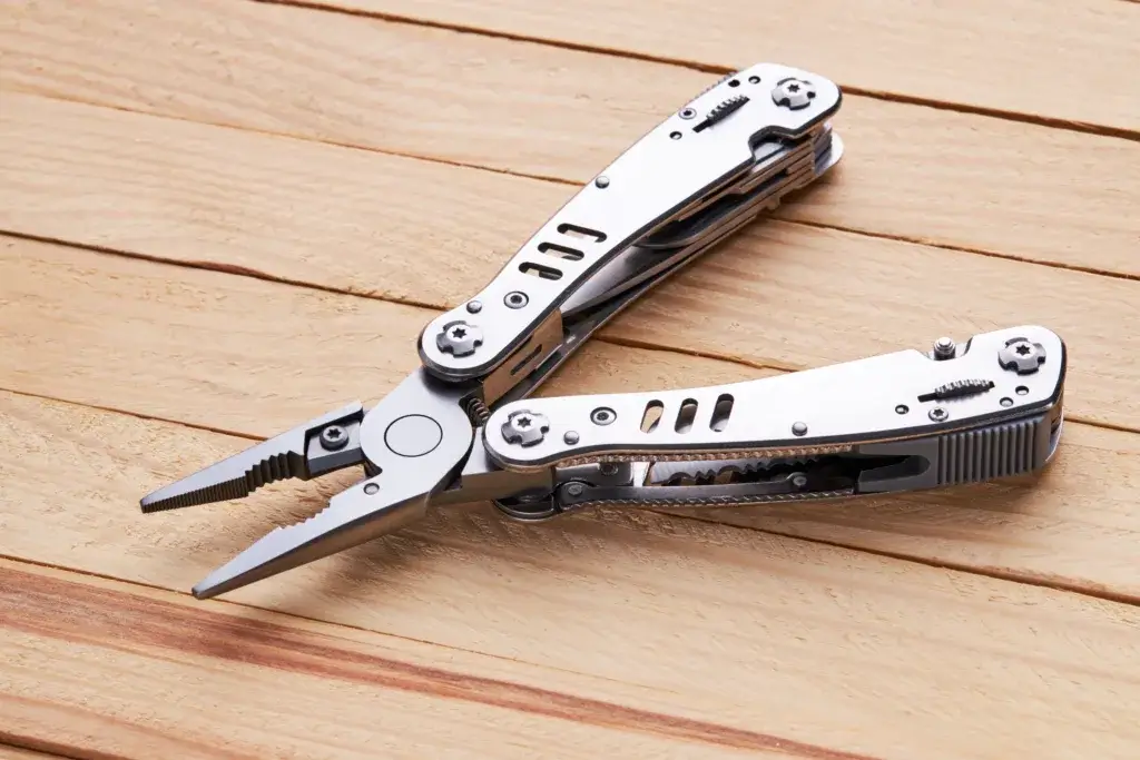 Silver multi tool lying on a wooden table.