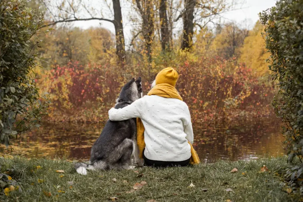 Woman and dog sitting next to each other autumn camping.
