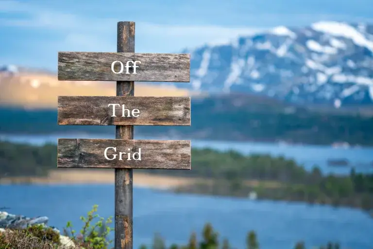 Wooden sign in front of a lake that says Off The Grid.