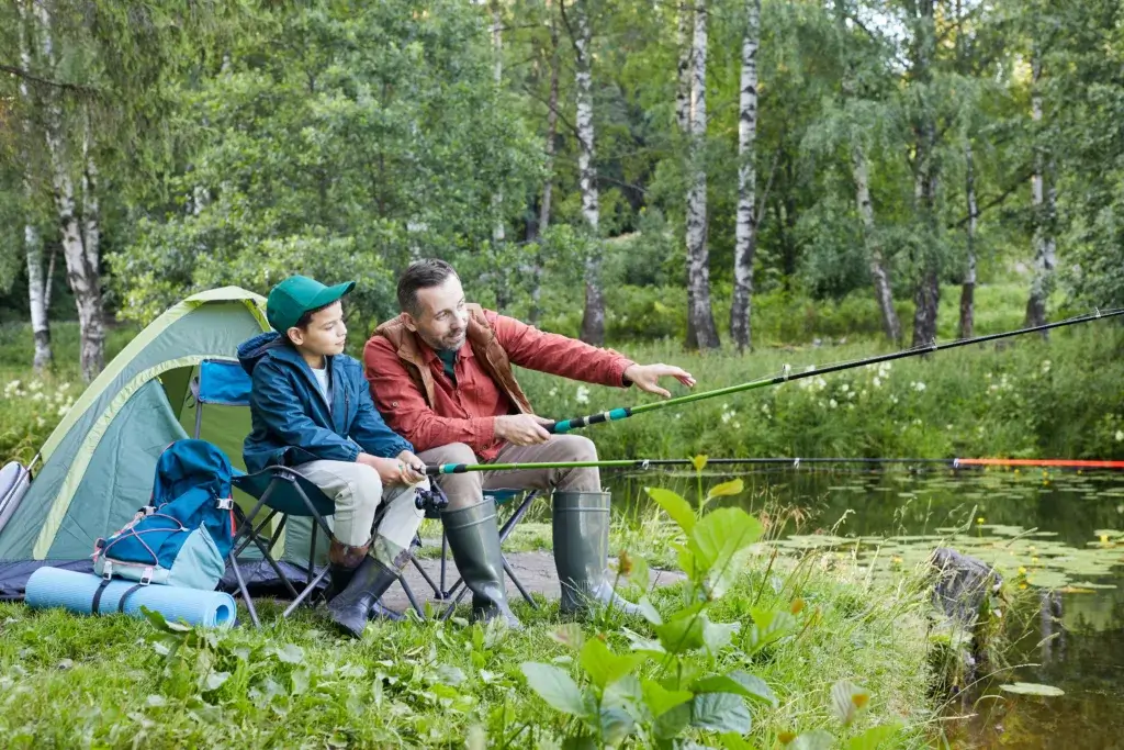 Father and son on a camping trip fishing together.